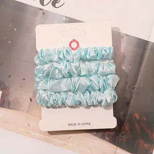 Detail view of light blue satin scrunchies set on professional white display card