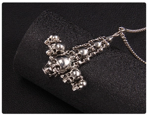 Macro view of silver skull stack detail on polished stainless steel gothic cross pendant