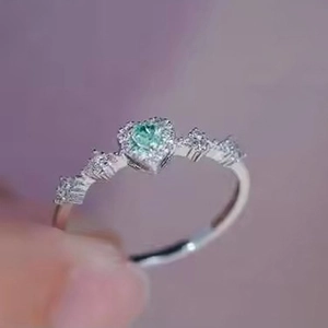 Detail of a heart-shaped light green gemstone ring with pavé diamonds in silver setting