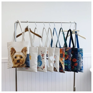 Detailed display of canvas tote bags with various dog, cat, and floral prints on a rack