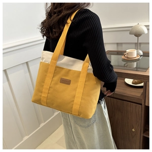 Detail of yellow and beige canvas tote bag with a brown leather Fashion patch