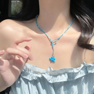 Blue beaded starfish necklace in Y-shape style worn by a model on a summer beach trip