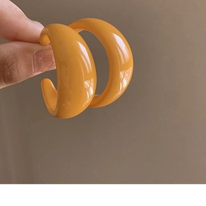 Retro orange acrylic C-shaped earrings with a smooth resin finish in minimalist hand-held view