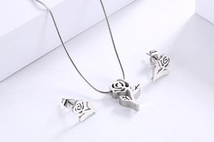Detailed view of silver rose necklace and earrings set on white geometric background
