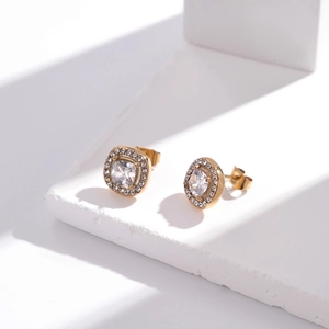 Boucles d'oreilles carrées dorées de luxe avec cristal sur un socle en pierre blanche