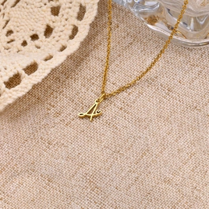 Detailed close-up of golden letter A pendant with heart motif on a knit fabric