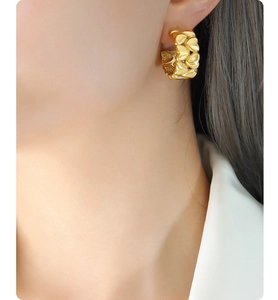 Close-up of golden hoop earrings with 3D heart-shaped elements worn by a model