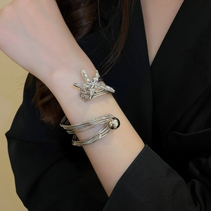 Nahaufnahme eines silbernen mehrlagigen Seestern-Armbands mit Kristallen am Handgelenk