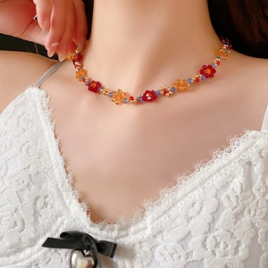 Détail du collier ras du cou floral en cristal coloré sur un haut en dentelle blanche