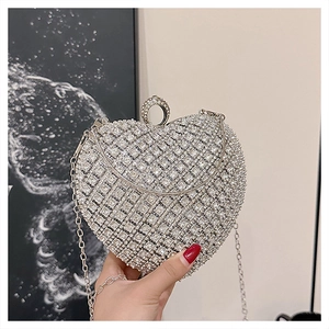 Detail of silver heart-shaped evening clutch bag with sparkling crystals and metal chain