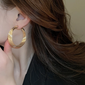 Close-up of elegant gold multi-layered hoop earrings worn by a model in a modern style
