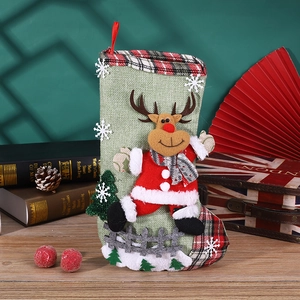 Detail of green linen Christmas stocking with a 3D plush reindeer and red plaid trim