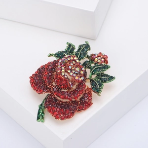 Detail of red rose brooch with green leaves and sparkling crystals on white cubes