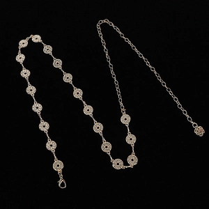Detail of gold chain belt with round diamond-encrusted links and a rose-shaped tail chain