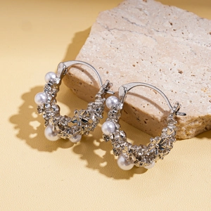 Detailed macro view of silver hoop earrings with white pearls and metal floral accents