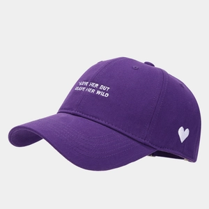 Close-up of white heart embroidery and text on a purple cotton baseball cap