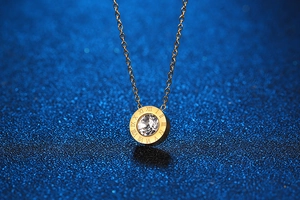 Macro shot of gold pendant necklace with roman numerals and central sparkling diamond