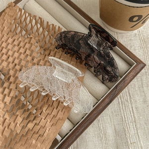 Elegant lace pattern hair claws in black and white styles on a vintage display tray