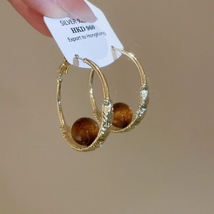 Detail of gold spiral hoop earrings with 925 silver needles and dark brown beads