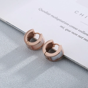 Gros plan détaillé de boucles d'oreilles en acier rose doré avec nacre blanche