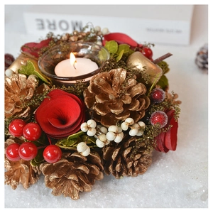 Detail of Christmas candle holder with red roses, gold pine cones, and red berries decor