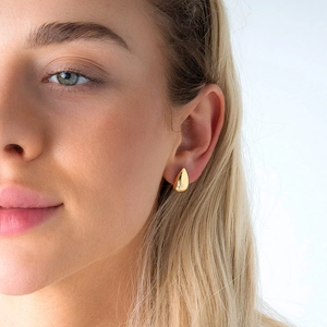 Boucles d'oreilles gouttes dorées polies portées par un mannequin au style élégant