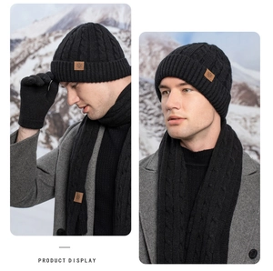 Detailed view of black cable knit winter set including beanie, scarf and gloves on a model