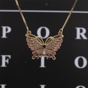 Close-up of golden butterfly necklace pendant with pink crystals and blue gemstone