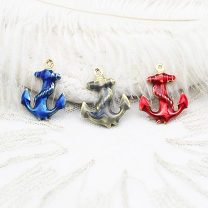Three colorful enamel anchor pendants in blue, grey, and red with gold metal frames