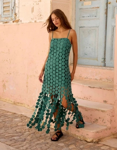 Detail of dark green midi dress with laser-cut circle patterns and tassel hemline