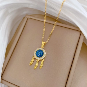 Detail of golden dreamcatcher necklace with a blue gemstone and sparkling crystals