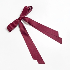 Detail of burgundy satin double bow hair clip with elegant silk texture on white background