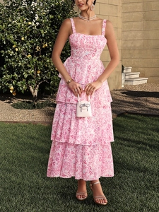 Floral print pink tiered maxi dress with thin straps worn in a sunny garden setting