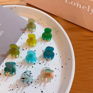 Set of nine mini acrylic hair claw clips in mixed colors on a white ceramic plate