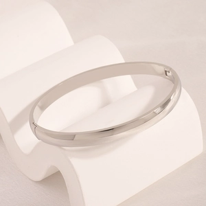 Close-up of polished stainless steel curved bangle with a smooth mirror finish and hinge