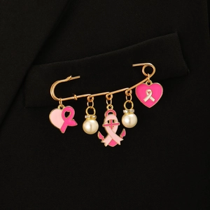 Detailansicht der rosa Brustkrebs-Schleifen-Anhänger und weißen Perlen an der Goldbrosche