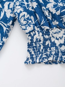 Dettaglio del ricamo floreale e smocking sulla maglia blu con scollo a V e maniche lunghe