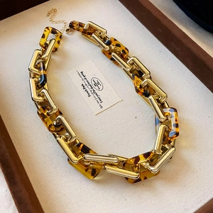 Detail of vintage chunky link necklace with gold metal and amber resin tortoiseshell texture