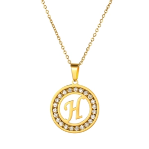 Close-up of golden letter H pendant with shimmering cubic zirconia pavé around circle