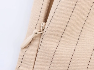 Détail de fermeture éclair invisible sur tissu en toile beige à fines rayures