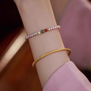 Detail of lavender pearl bracelet with green agate and matte gold bangle on wrist