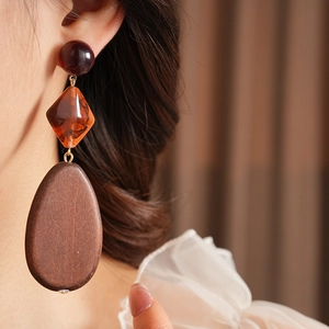 Detail of artistic resin and wood geometric drop earring worn by a female model