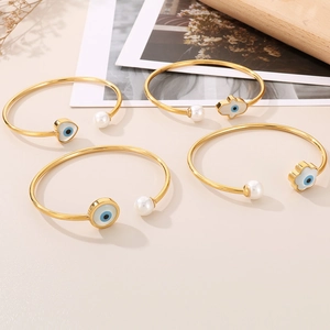 Lot de quatre joncs dorés en acier titane avec œil porte-bonheur, perle et cœur