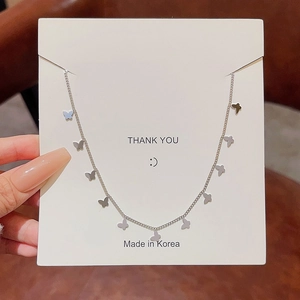 Silver stainless steel butterfly necklace with multiple pendants on a white display card
