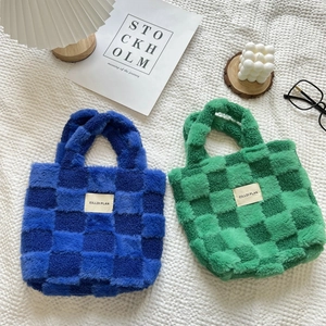 Close-up of plush checkerboard bucket bags in blue and green on a soft textured rug