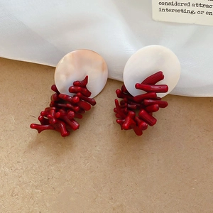 Detail of red coral resin branches and white shell disc stud earrings on wood base