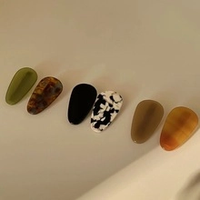 Close-up of minimalist hair clips in olive green, tortoiseshell, and marble patterns