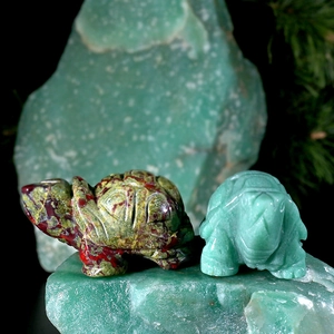 Macro detail of hand-carved natural green jade and jasper turtle statues on raw stone