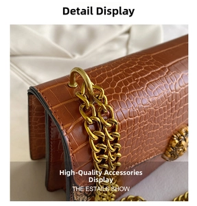 Detail of brown crocodile pattern handbag with golden lion head buckle and chunky chain