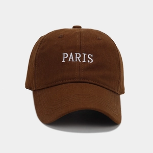 Detailed close-up of white PARIS embroidery on a dark brown cotton baseball cap
